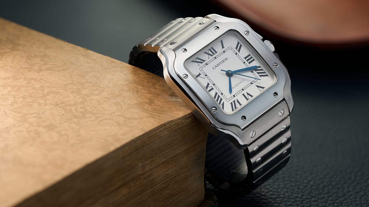 A Cartier Santos wristwatch resting on a wooden block